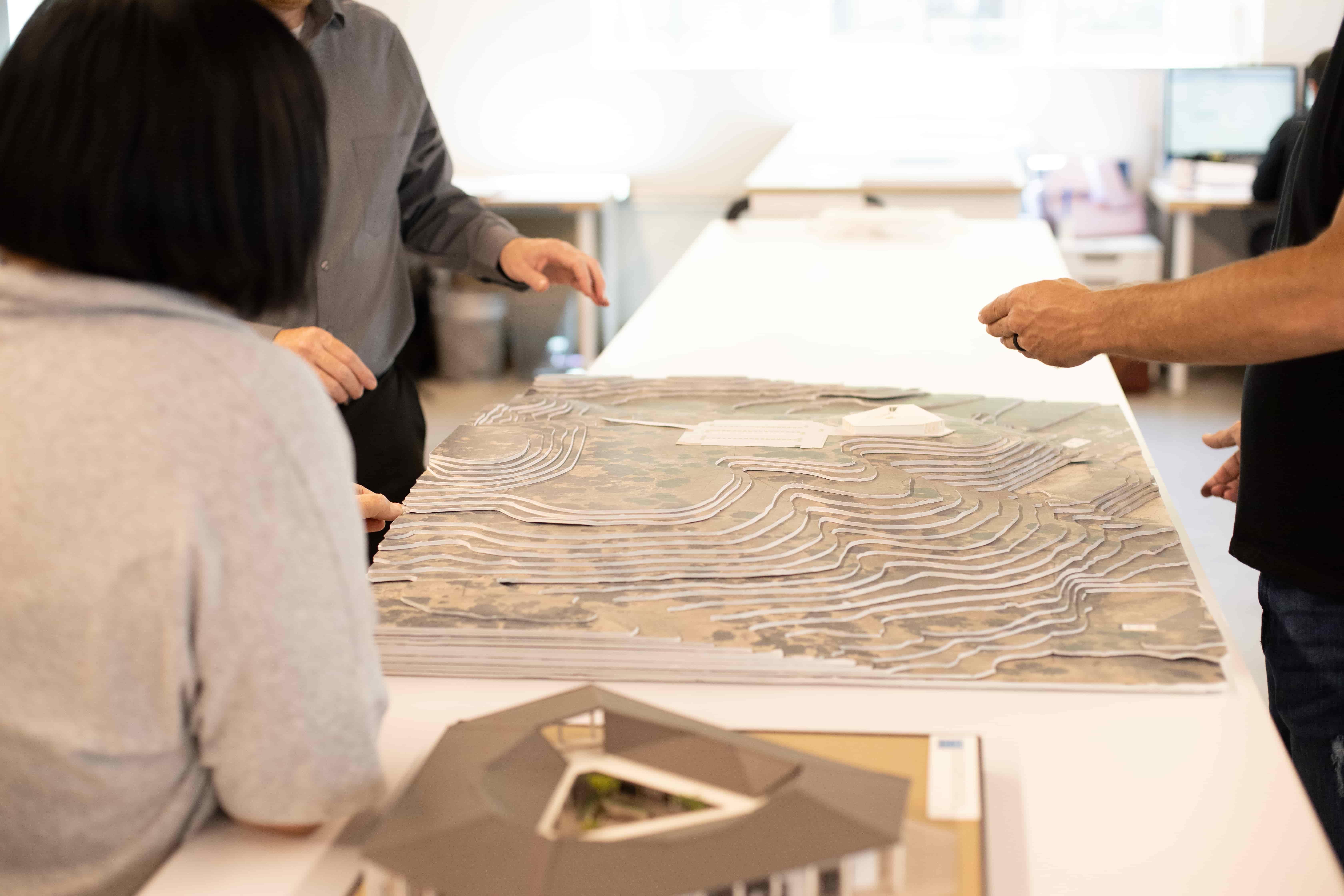Architects at Paul Halajian Architects talk around a terrain model of a project
